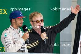 (L to R): Race winner and World Champion Lewis Hamilton (GBR) Mercedes AMG F1 on the podium with Sir Elton John (GBR). 25.10.2015. Formula 1 World Championship, Rd 16, United States Grand Prix, Austin, Texas, USA, Race Day.